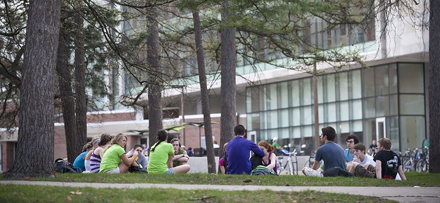 Photo of students sitting on the ground outside of wells hall